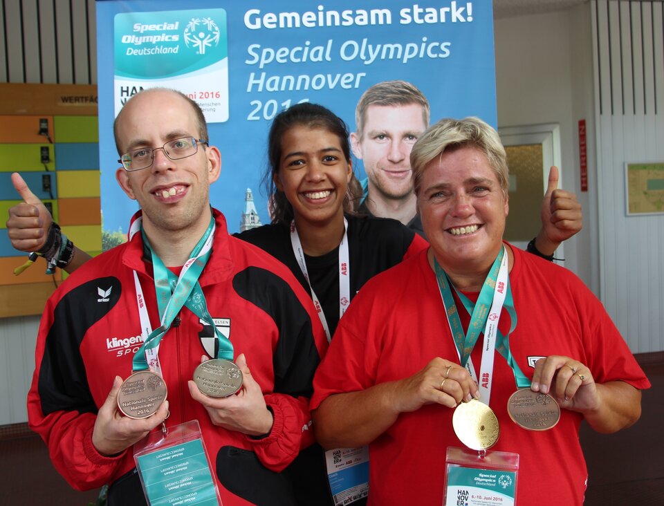 Zwei Sportler der TuRa Elsen zeigen stolz ihre Medaillen. Unsere FSJlerin Johanna freut sich mit ihnen.