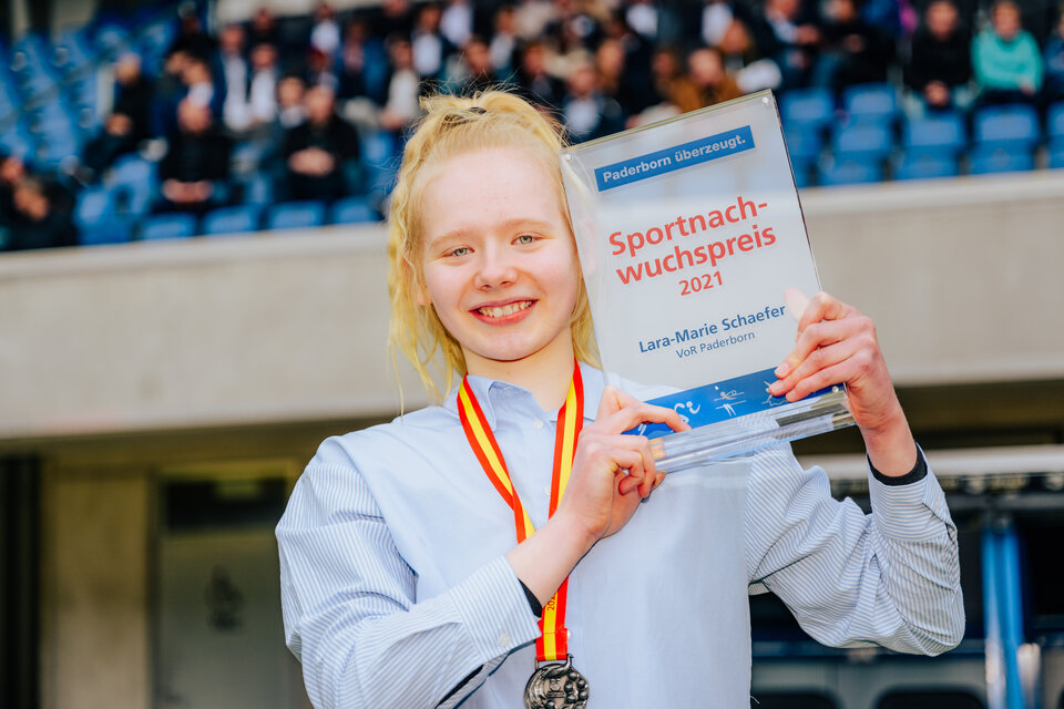 Lara-Marie Schaefer hält stolz den Sportnachwuchspreis in die Kamera.